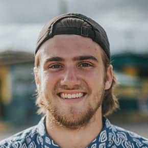 Smiling person wearing a cap outdoors.