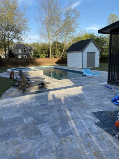 Backyard pool with chairs and a shed nearby.