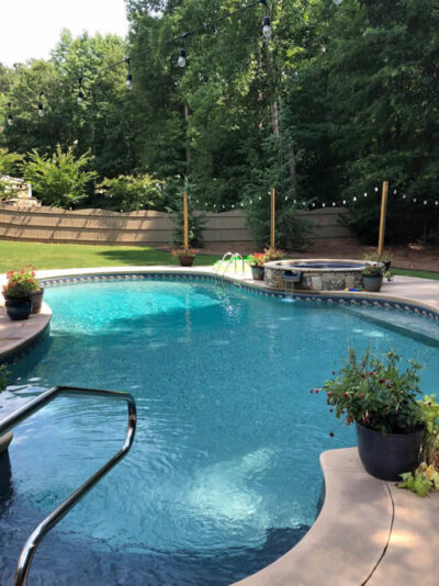 Backyard pool with surrounding greenery and patio.