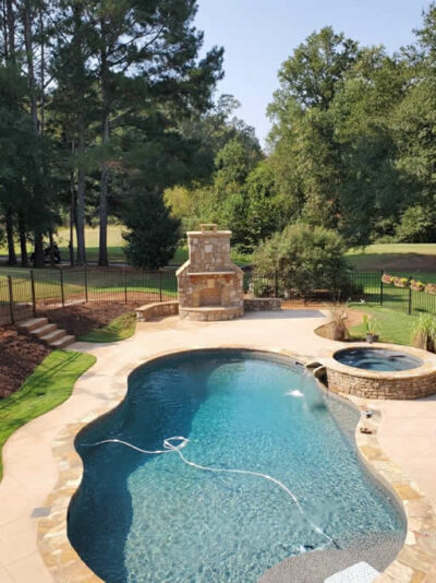 Backyard pool and hot tub with surrounding greenery.