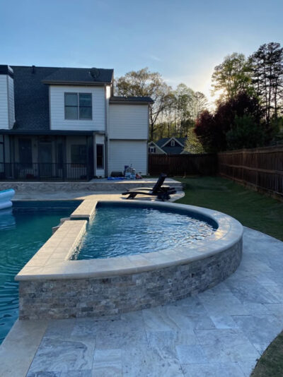 Backyard pool at sunset with patio furniture.