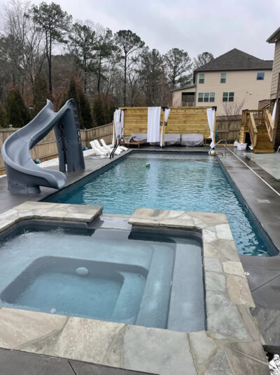 Backyard pool with slide and hot tub.