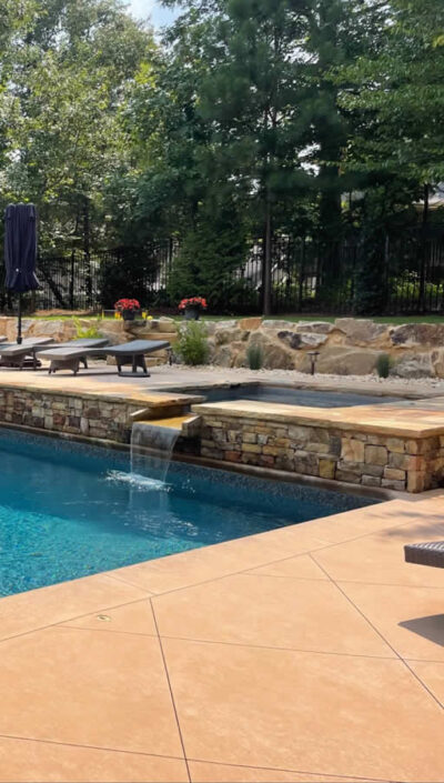 Serene pool with waterfall and sun loungers.
