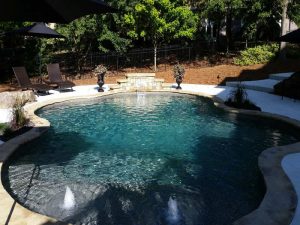 Backyard pool with fountains and lounge chairs.