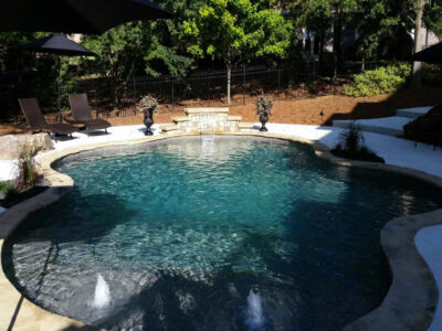 Backyard pool with fountains and lounge chairs.