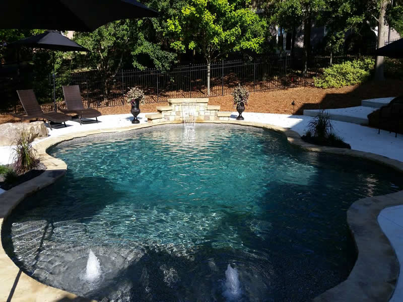 Backyard pool with fountains and lounge chairs.