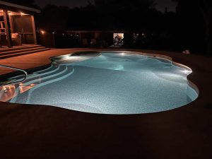 Illuminated swimming pool at night with steps.