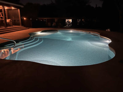 Illuminated swimming pool at night with steps.