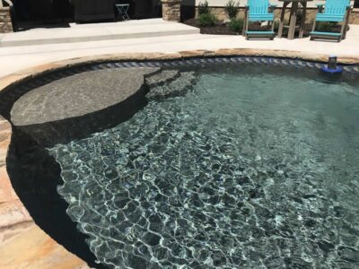 Clear backyard pool with patio and chairs