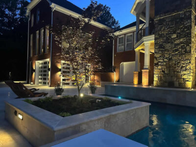 Nighttime view of illuminated modern house with pool.