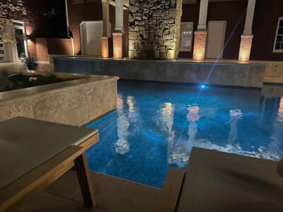 Nighttime view of illuminated outdoor pool area.