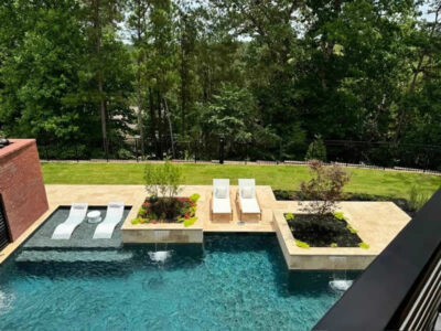 Luxury outdoor pool with loungers and greenery.