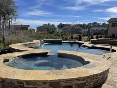 Stone pool and hot tub with water features.