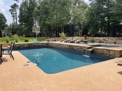 Backyard pool with waterfall and basketball hoop.