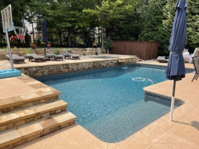 Backyard pool with chairs and umbrellas.
