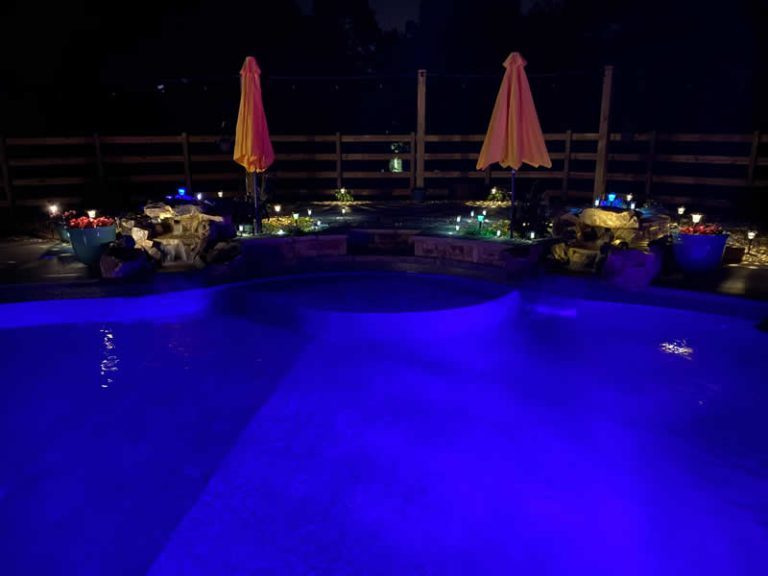 Nighttime pool with purple lights and umbrellas.