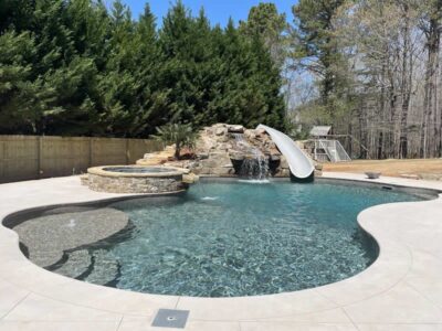 Backyard pool with slide and waterfall feature.