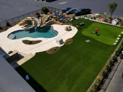 Backyard with pool, slide, and artificial grass.