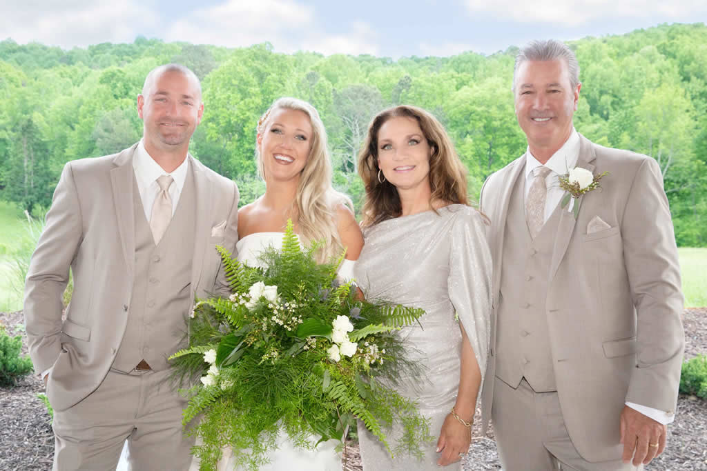 Bride and three guests in formal attire outdoors.