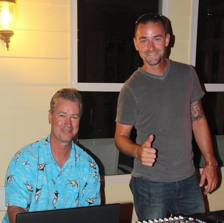 Two men smiling indoors, one giving thumbs up.