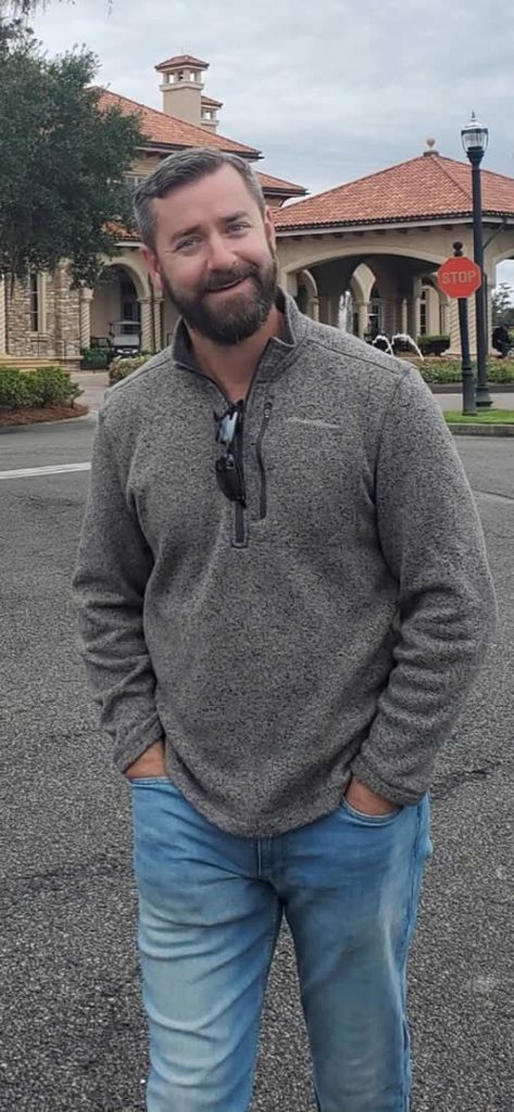 Person standing outside building with stop sign.