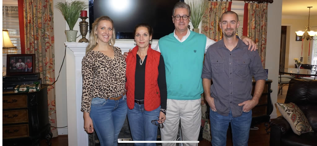 Four people smiling in a living room setting.