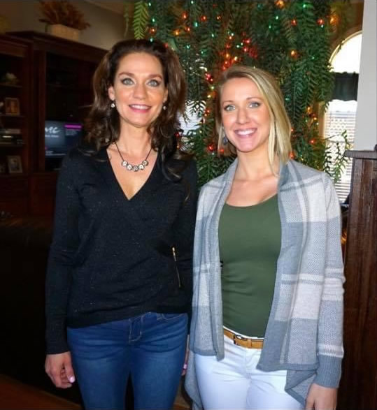 Two women smiling in front of decorated tree.