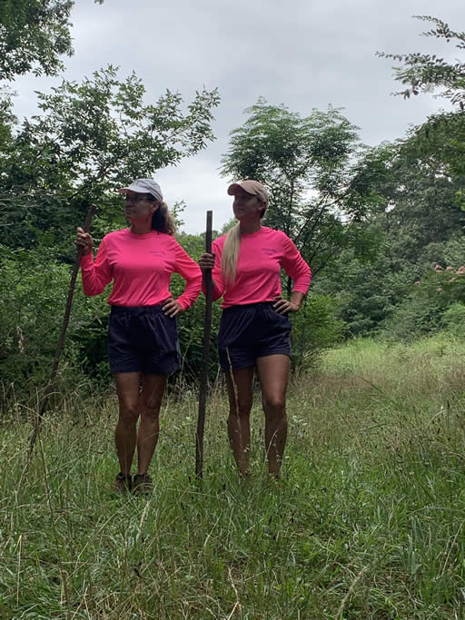 Two women hiking with sticks in forest.