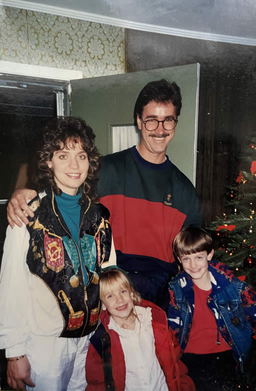 Family smiling near Christmas tree indoors.