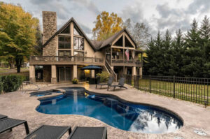 A-frame home with pool, deck, and autumn trees