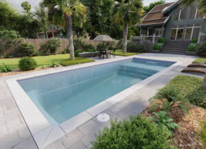 Modern backyard pool surrounded by palms and patio seating
