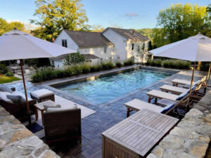 Backyard swimming pool with lounge chairs and white umbrellas