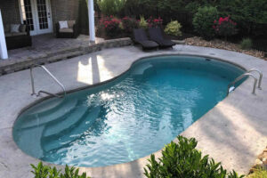 Curved backyard pool with patio seating and flowering garden