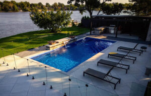 Modern riverside pool patio with lounge chairs and outdoor kitchen