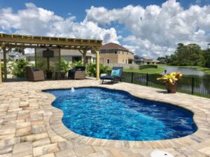 Backyard pool beside pergola overlooking pond