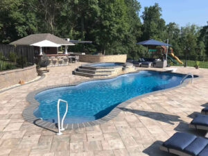 Curved backyard pool with spa, patio, and lounge seating