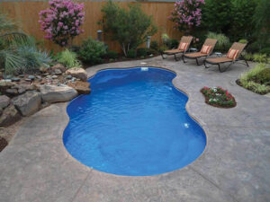 Curved backyard pool with loungers and landscaped garden