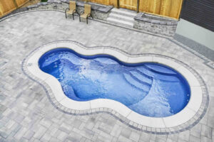 Freeform backyard pool surrounded by gray stone pavers